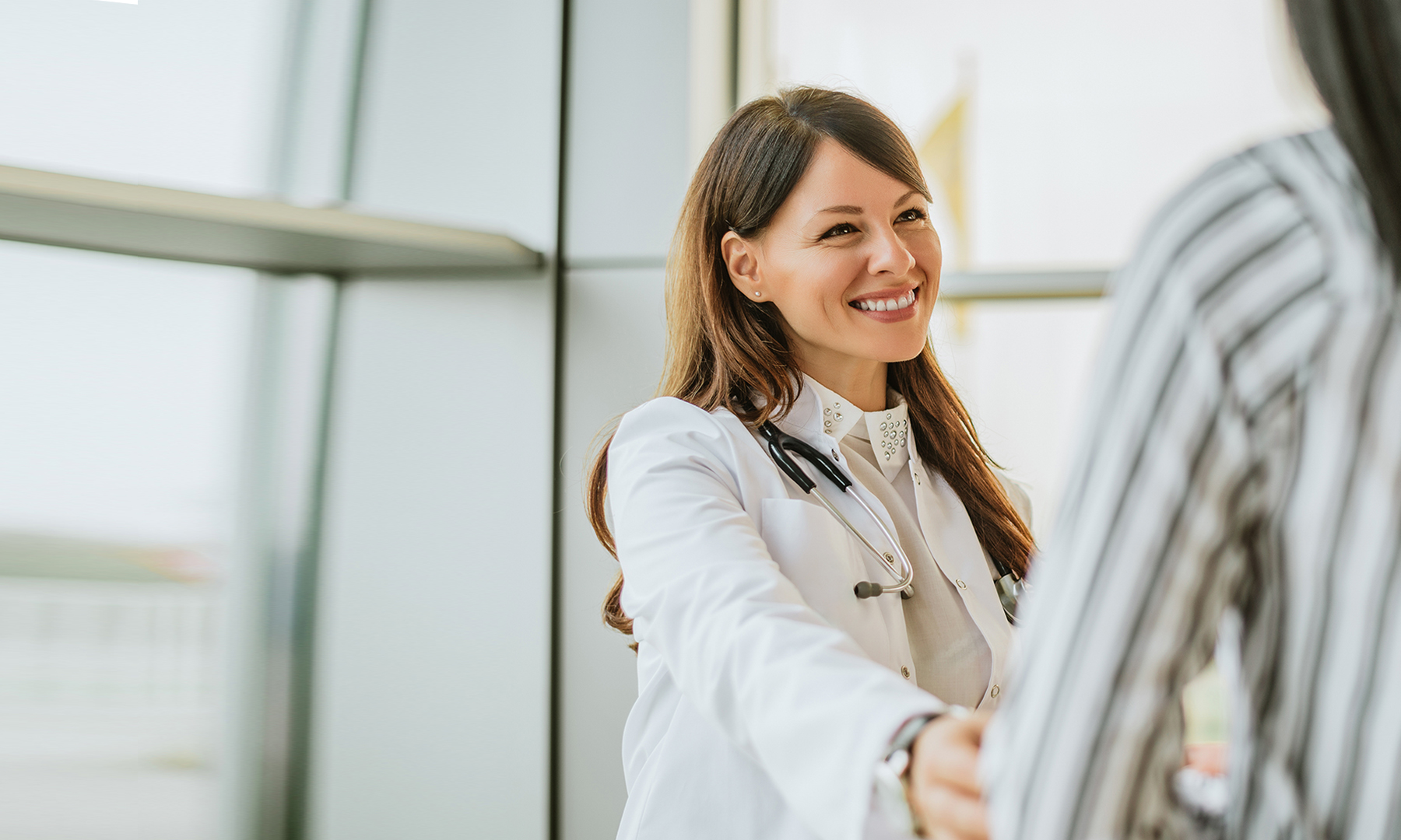 Ärztin begrüßt lächelnd eine Patientin.