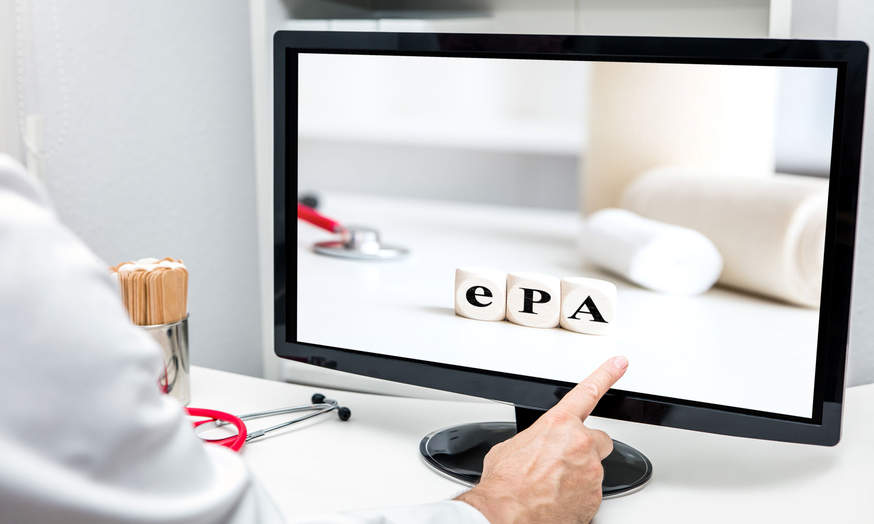 Ein Arzt in der Praxis berührt seinen Monitor, auf diesem sind Würfel mit der Aufschrift ePA für "elektronische Patientenakte" abgebildet. 